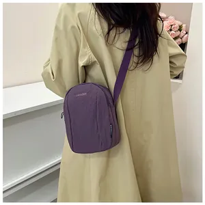 Detailed view of a purple waterproof nylon crossbody bag with matching shoulder strap