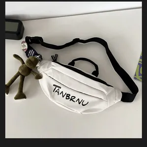 Detail of white crossbody bag with black straps, charms and pins on white desk