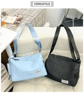 Detail of light blue and charcoal grey canvas crossbody bags with adjustable wide straps