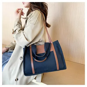Detail of navy canvas and brown leather stitching on a large fashion tote bag
