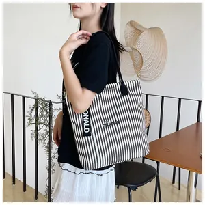 Close-up of black and white striped canvas tote bag with woven Donald strap