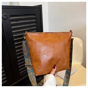 Detail of vintage brown PU leather bag featuring a colorful ethnic embroidered wide strap