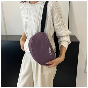 Close-up of deep purple half-moon crossbody bag with black strap and silver zipper