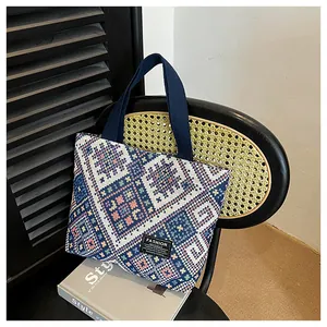 Detail of ethnic geometric woven tote bag with navy wide straps on a stylish chair