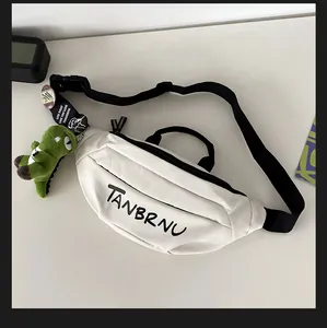 Detail of white canvas waist bag with black logo, dinosaur plush, and badges