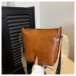 Close-up of brown PU leather tote bag with vintage texture and colorful geometric strap