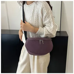 Close-up of deep purple nylon saddle bag worn by a model in a casual knit sweater