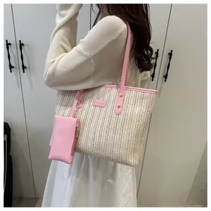 Detail of straw tote bag featuring pink leather trim and matching zip pouch attachment