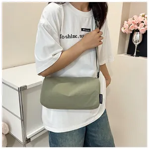 Detail of light olive nylon crossbody bag with woven side label and adjustable strap
