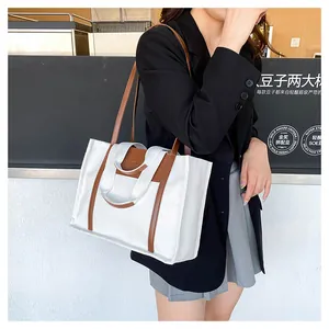 Detail of canvas tote bag showing brown leather straps and spacious modern minimalist design