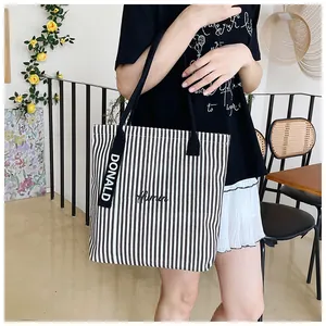 Detail of striped canvas tote bag featuring Himn embroidery and Donald decorative strap