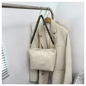 Detail view of beige crossbody tote bag with ethnic patterned wide strap on a hanger