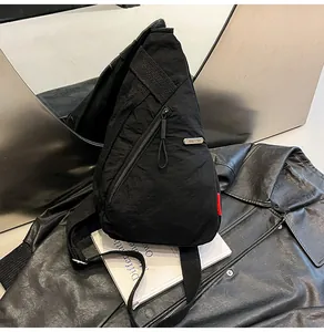 Κοντινό πλάνο μαύρης τσάντας στήθους από νάιλον με διαγώνιο φερμουάρ και μεταλλικό σήμα