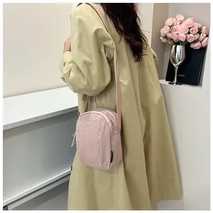 Detailed view of pink nylon crossbody bag with double zippers and adjustable strap