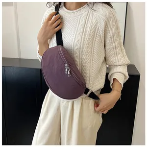 Detail of a deep purple nylon crescent moon sling bag with adjustable strap and metal zippers