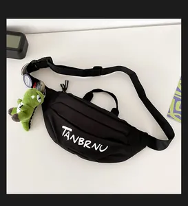 Detail of black canvas chest bag with white logo, plus green dinosaur plush and badges