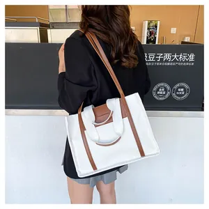 Canvas and leather tote bag detail worn by a model in a stylish cafe setting