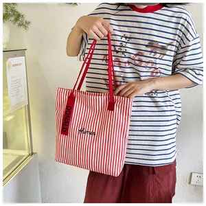 Detail of red striped canvas tote bag with Humin embroidery and red shoulder straps