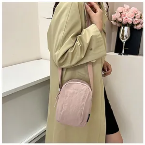 Detail of pink nylon crossbody bag with LANWEISER logo on a minimalist background