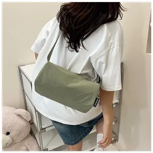 Olive green nylon crossbody bag detail showing wrinkled texture and side brand tag