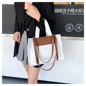 Detail of the canvas tote bag showing the brown leather trim and embossed fashion text