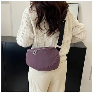 Rear view of a model wearing a purple crescent nylon crossbody bag with adjustable strap
