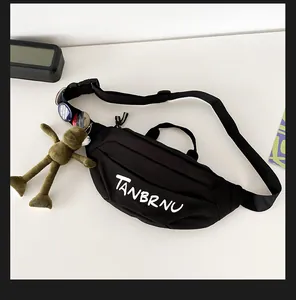 Detail of black canvas chest bag featuring TANBRNU logo, badges and green bear charm