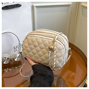 Dettaglio borsa a tracolla trapuntata beige con catena dorata e tripla cerniera