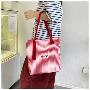 Detail of red and white striped canvas tote with Humin embroidery and woven charm strap