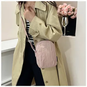 Close-up of pink nylon crossbody bag with adjustable strap and waterproof texture