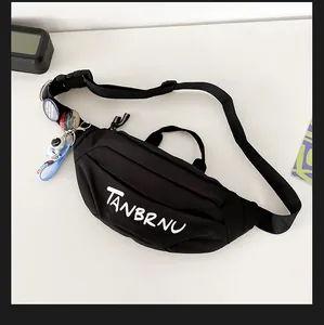 Detail of black nylon chest bag with white artistic lettering and astronaut charm