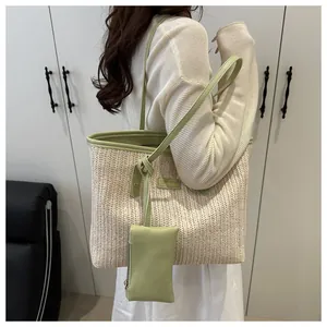 Detail of woven straw tote bag featuring green leather trim and matching small pouch