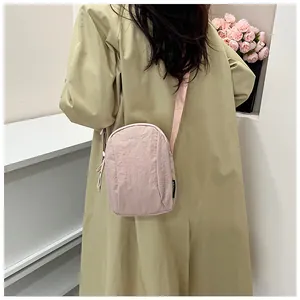 Close-up of a light pink nylon crossbody bag with zipper detail and woven shoulder strap