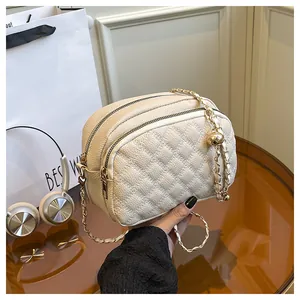 Dettaglio borsa trapuntata beige con catena dorata e ciondolo a sfera chic