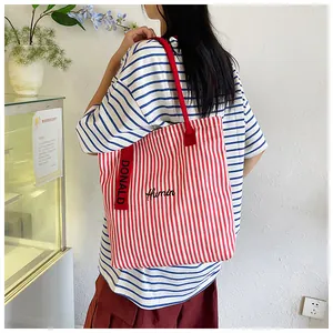 Detail view of large canvas tote bag with red stripes and embroidered Humin logo