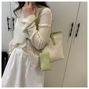 Close-up of woven straw tote bag with light green leather straps and hanging charm pouch