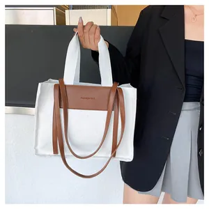 Detail of canvas tote bag with leather panel featuring FASHION BAG embossed text