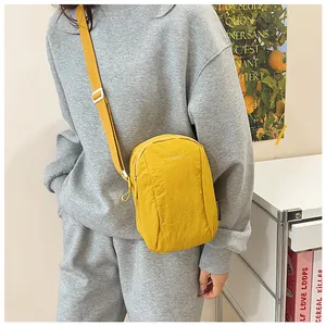 Detail of yellow nylon crossbody bag with adjustable strap and brand embroidery logo