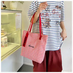 Detail of red and white striped canvas tote bag featuring black Humin script embroidery