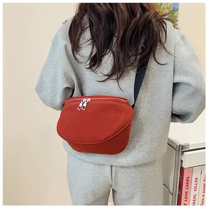 Detail view of the rust red crossbody bag with silver zippers and wide black strap
