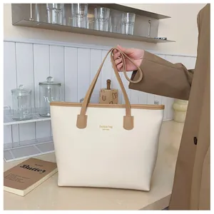 Detalle del bolso tote de cuero crema con asas marrones e impresión de New York