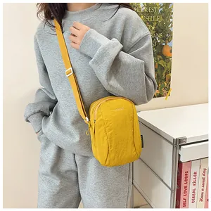 Detail of a bright yellow waterproof nylon crossbody bag with adjustable strap and logo