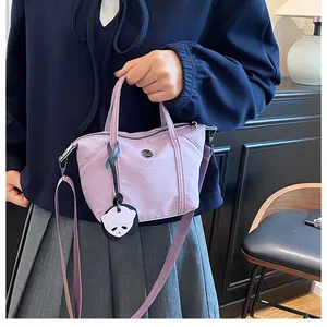 Detail of light purple nylon mini tote bag with panda pendant and detachable strap