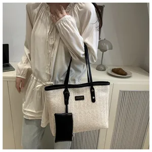 Detail of woven straw tote bag with black leather straps and hanging zip pouch
