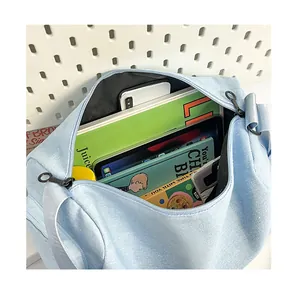 Spacious interior of light blue canvas tote bag storing books, tablet, and water bottle