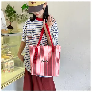 Detail of red and white striped canvas tote bag with Humin embroidery and decorative strap