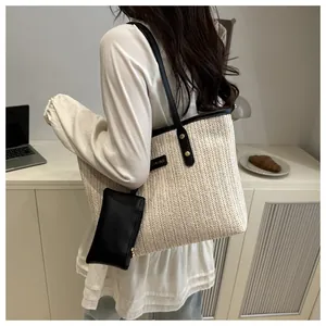 Close-up of woven straw tote bag with black trim and small leather pouch detail