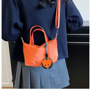 Close-up of a mini orange nylon tote bag featuring a cute panda charm and shoulder strap