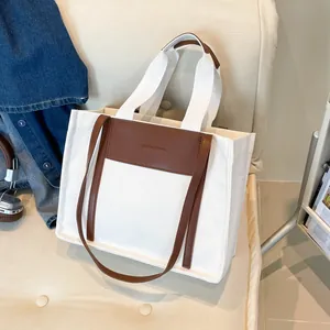 Large canvas and leather tote bag for women shown on a cozy sofa in a lifestyle setting