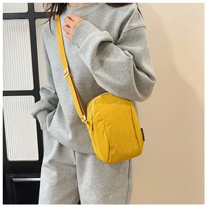 Detailed view of yellow waterproof nylon crossbody bag worn with casual gray sportswear